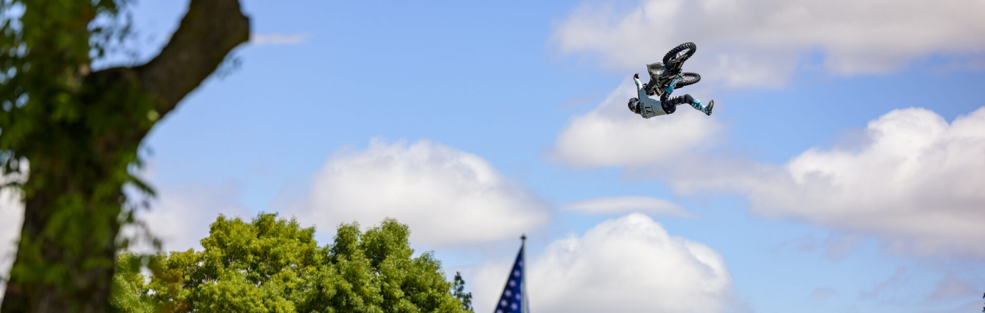 Dirt Bike Rider in mid-air flight. A black inflatable landing ramp is in view for the rider to land on.