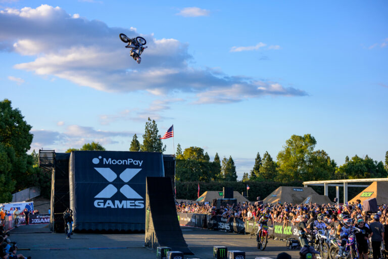 Dirt Bike Rider in mid-air flight. A black inflatable landing ramp is in view for the rider to land on.