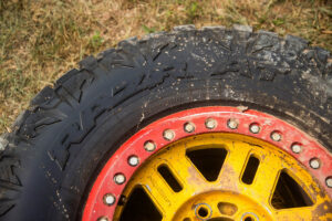 Close-up of a Maxxis off-road tire on a customized colored wheel rim.