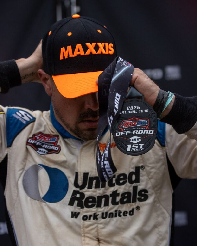 Jimmy Henderson in Maxxis hat pulling a winning medal over his head