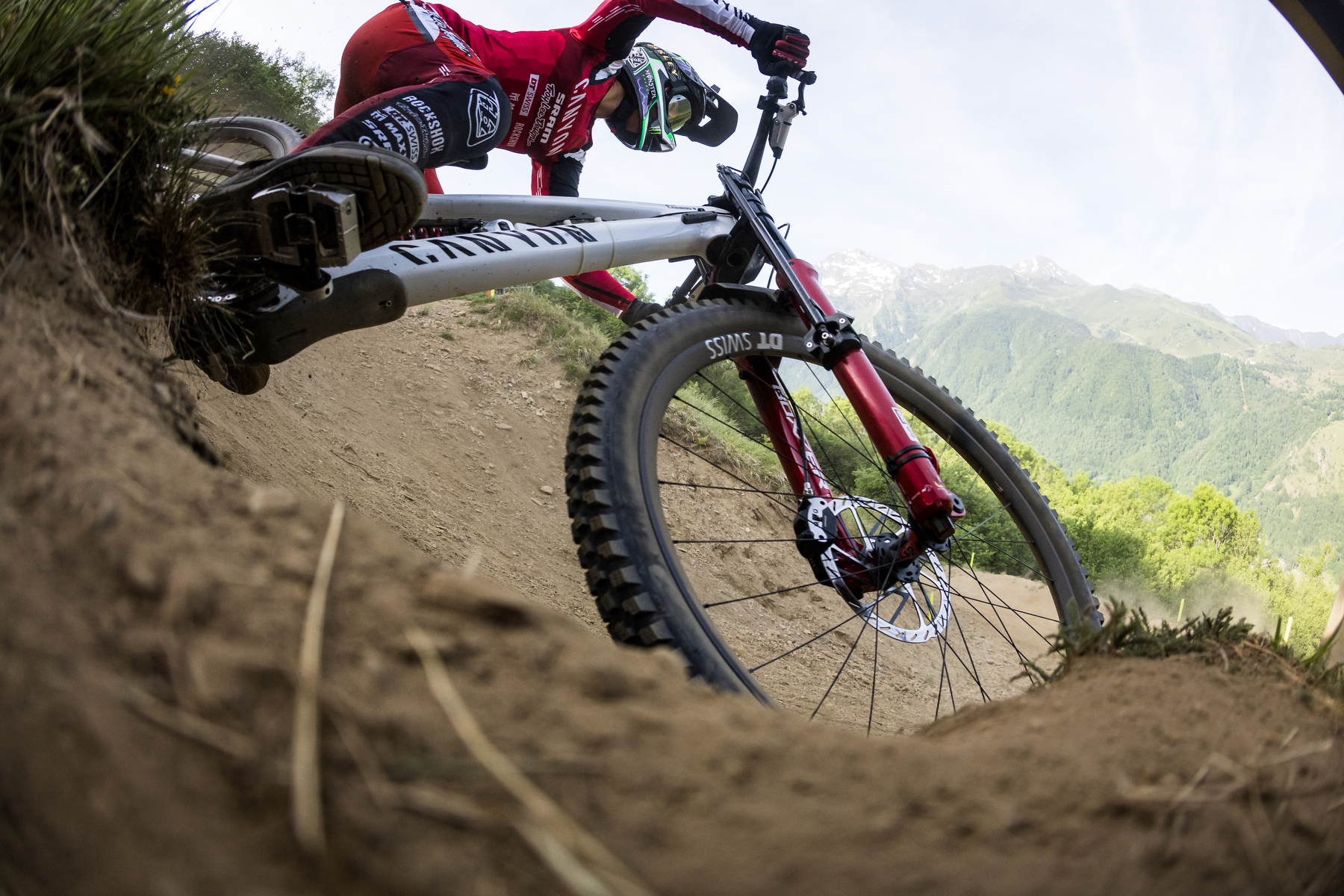 Close-up of a downhill mountain bike carving through a berm, highlighting the cornering grip and support of the Maxxis Minion DHX.